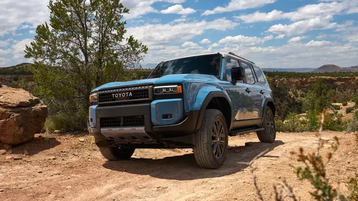 2024 Toyota Land Cruiser driving through rugged terrain with full-time four-wheel drive