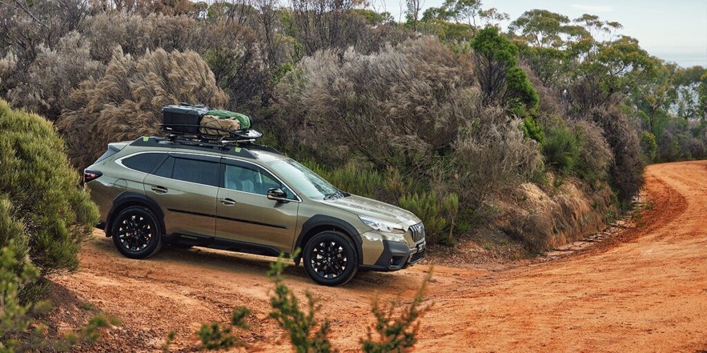 Subaru Outback driving through trees and showcasing its compact camping capabilities."