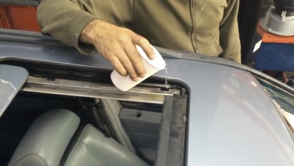 Image of water being poured into a sunroof testing leaks.