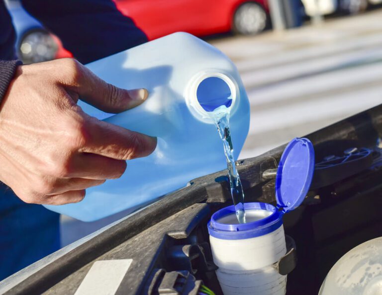 Person pouring the Best Windshield Wiper Fluid for Winter into a car reservoir for clear visibility